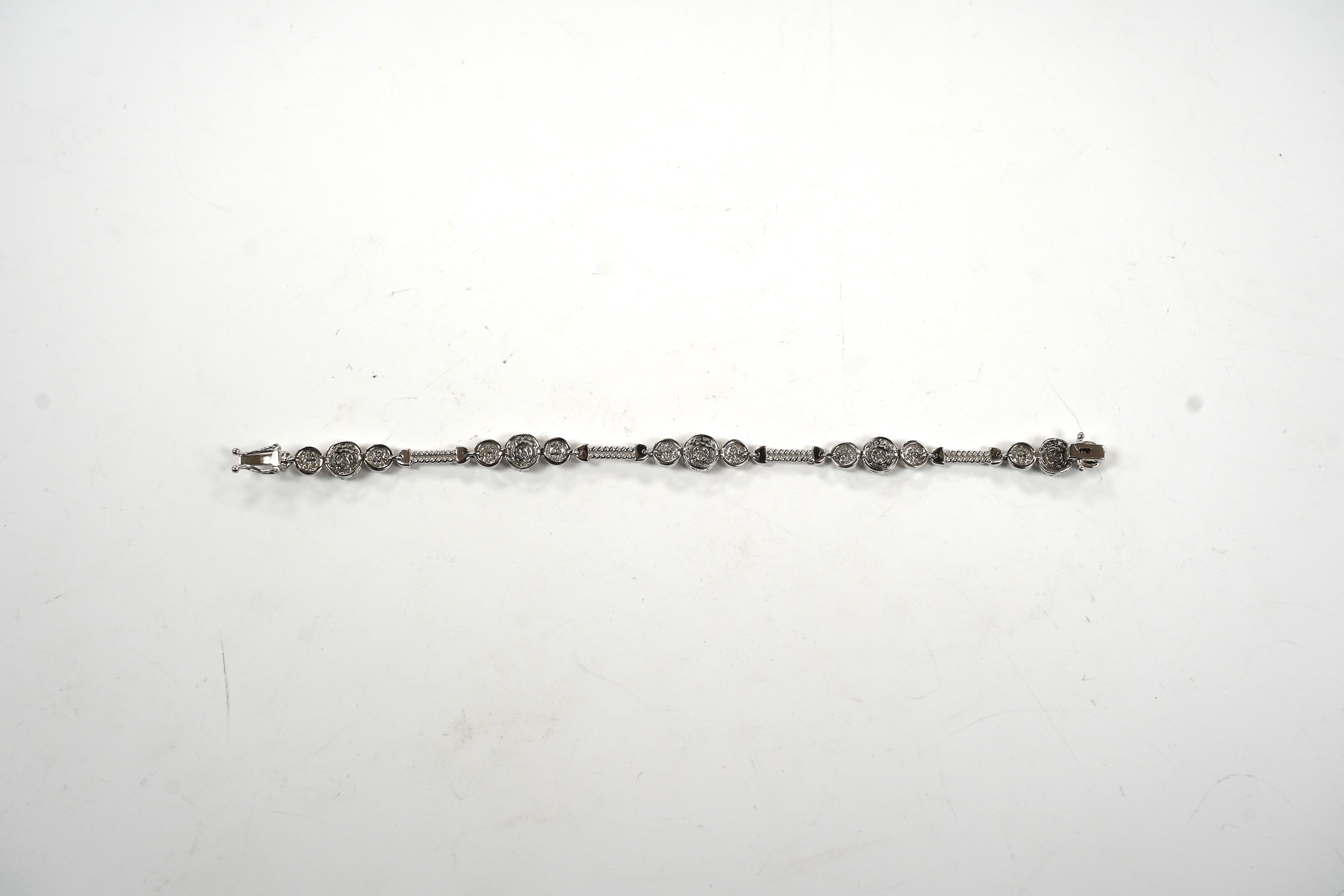 A modern 14k white metal and diamond cluster set line bracelet, the total diamond weight approximately 2.00ct, 16.5cm, gross weight 11.1 grams.